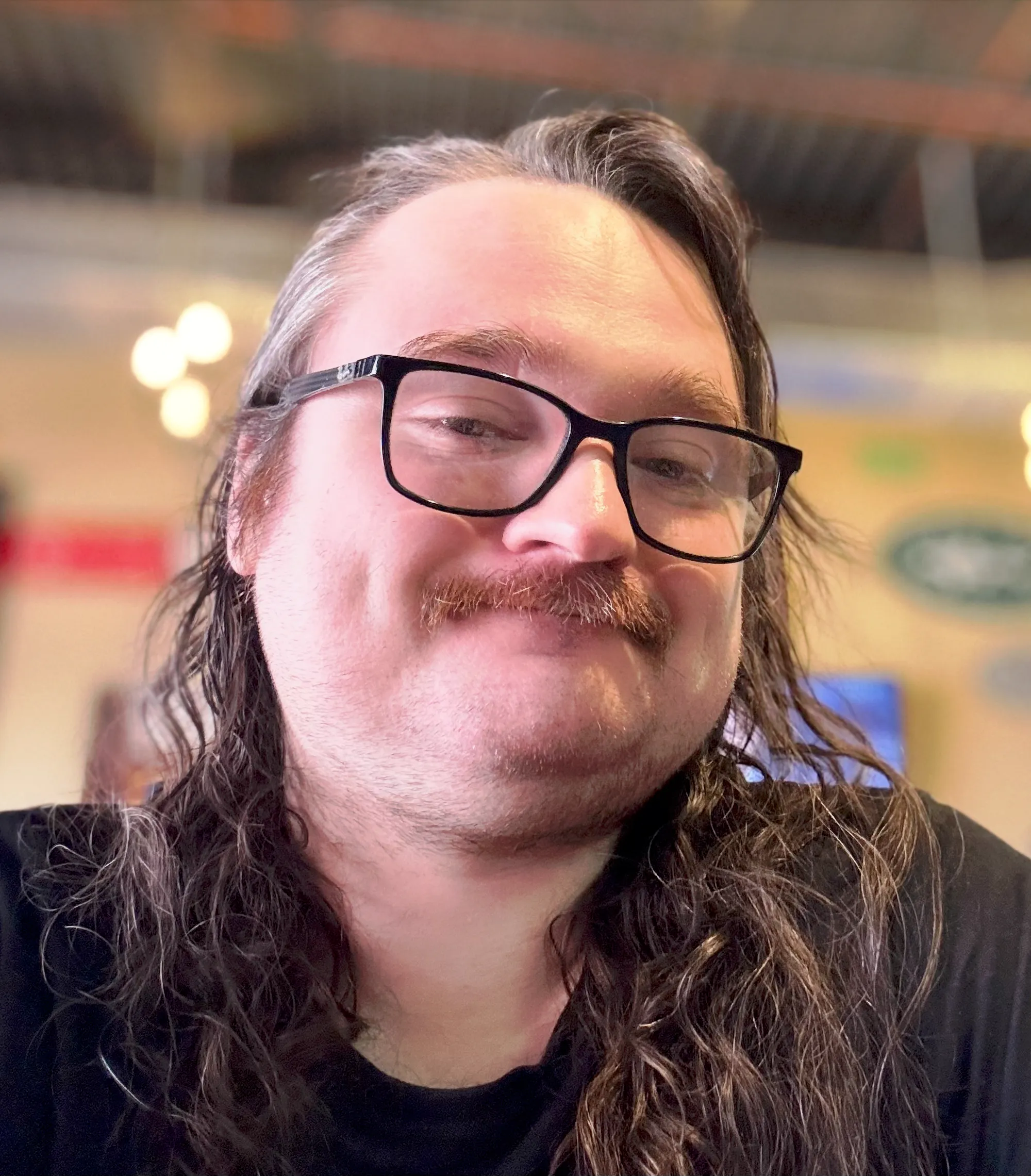 Lou Stella smiling in a black shirt and black glasses